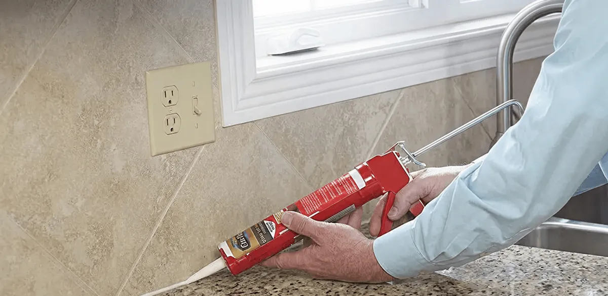 Handyman applying caulk along a kitchen backsplash and countertop seam in Fort Collins, CO